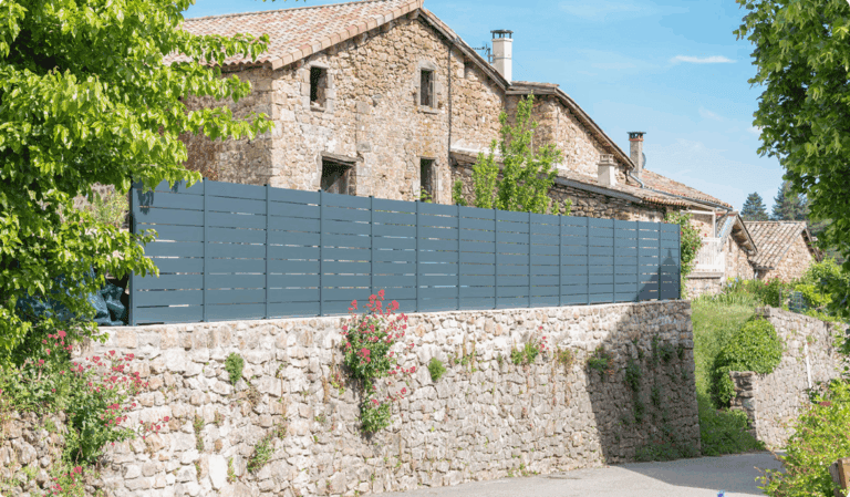 Clôture en aluminium moderne installée dans un jardin paysagé avec mobilier extérieur